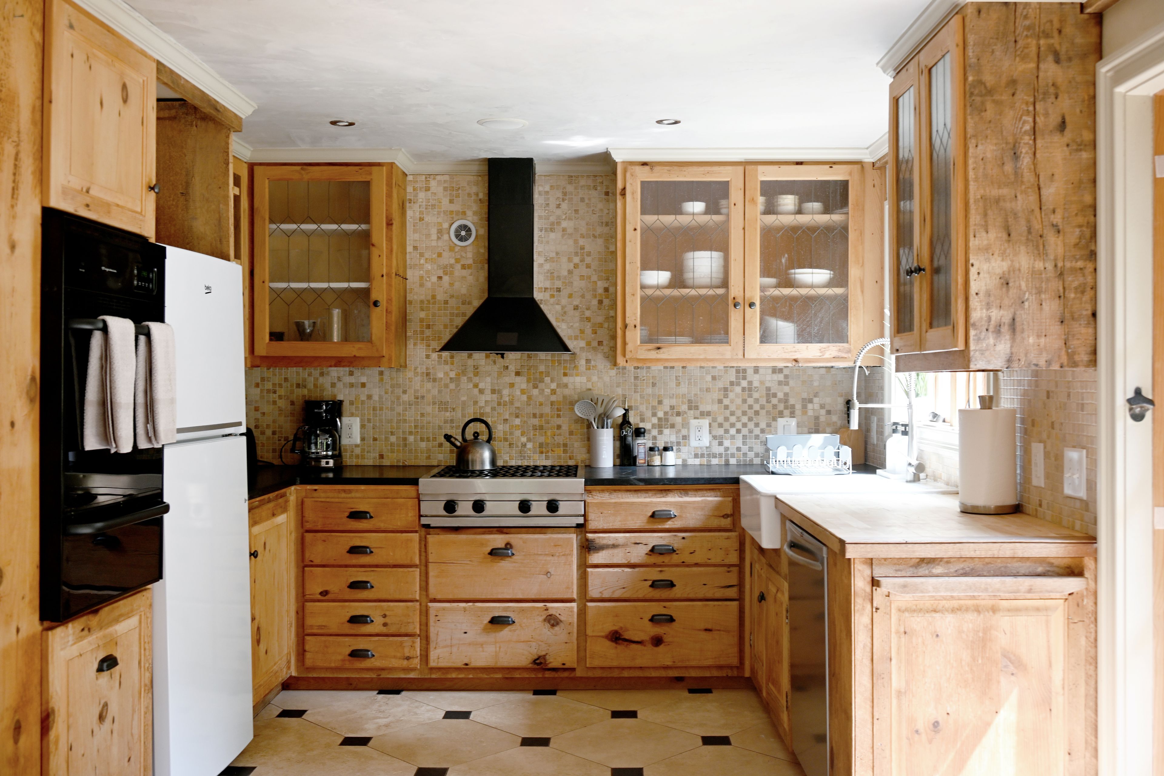 Een keuken met houten kastjes, een fornuis en een koelkast.