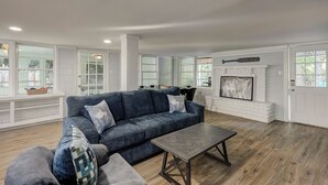 A spacious living room with a blue sofa, a coffee table, and a fireplace. - Sunset Rentals | Beachgate at Starfish 9 Dr. (Hilton Head Island)