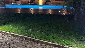 A modern outdoor pool area with seating and a wooden wall backdrop. - Logement Maltus (Lussac)