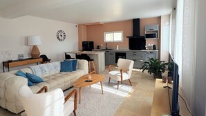 A modern living room with a sofa, chairs, a coffee table, and a TV. - Logement Maltus (Lussac)