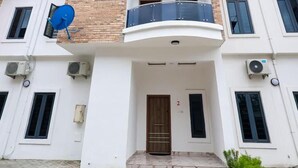 A two-story building with a balcony, satellite dish, and air conditioning units. - Exclusive 3-bed Apartment in Lagos (Lekki)