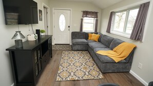 A living room with a sectional sofa, a flat-screen TV, a console table, and a patterned rug. - Entire 2 Bedroom Home (Elyria)