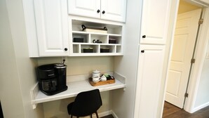 A compact kitchenette with white cabinetry, a coffee maker, and a small seating area. - Entire 2 Bedroom Home (Elyria)