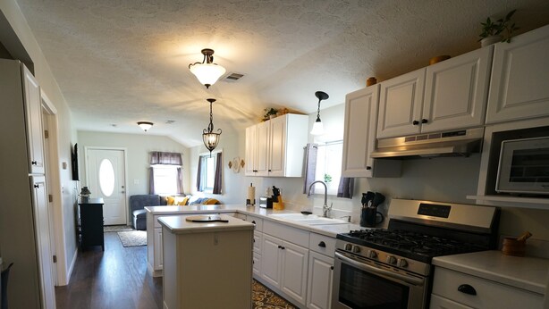 A modern kitchen with white cabinets, stainless steel appliances, and a central island. - Entire 2 Bedroom Home (Elyria)