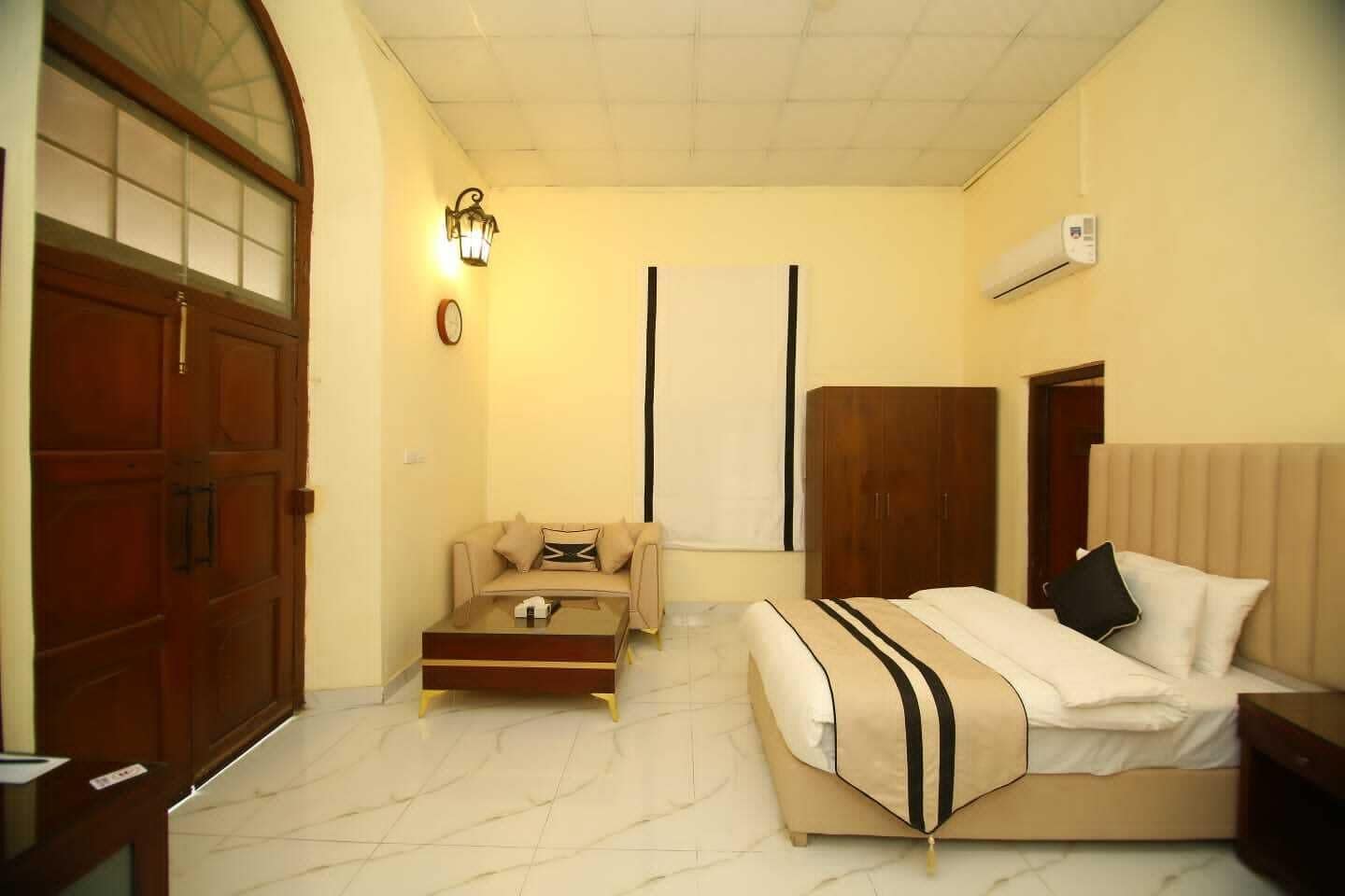 A hotel room with a bed, a sofa, a coffee table, a wardrobe, and a large window with a view.