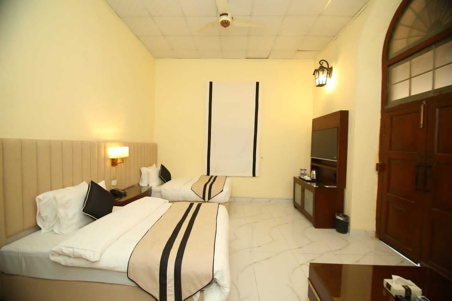 A hotel room with two beds, a TV, a desk, and a wardrobe.