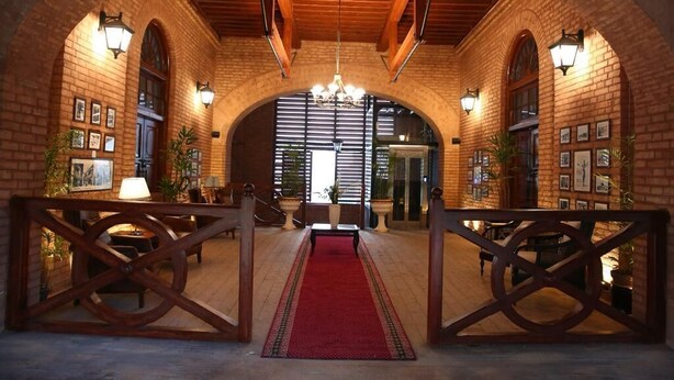 An arched hallway with brick walls, wooden beams, and a red carpet leading to a door. - Peshawar Barracks Estb 1867 (Peshawar)