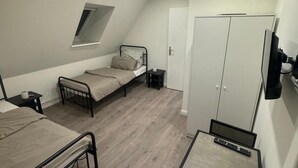 A dormitory room with two single beds, a desk, a wardrobe, a TV, and a window. - Gemütliche 2-zimmer Wohnung in Lübeck (Lübeck)