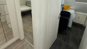 A room with a bed, a small kitchenette, and a radiator. - Gemütliche 2-zimmer Wohnung in Lübeck (Lübeck)