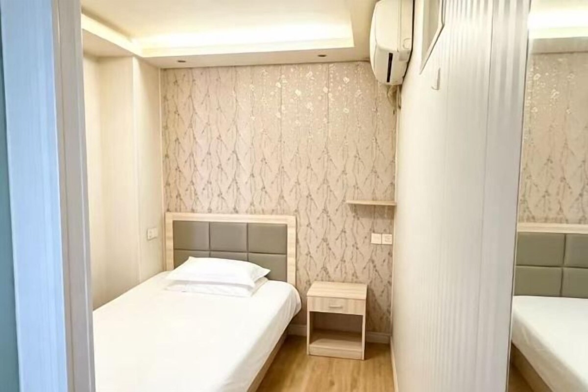 Une chambre d’hôtel avec deux lits, une table de chevet et un climatiseur fixé au mur.