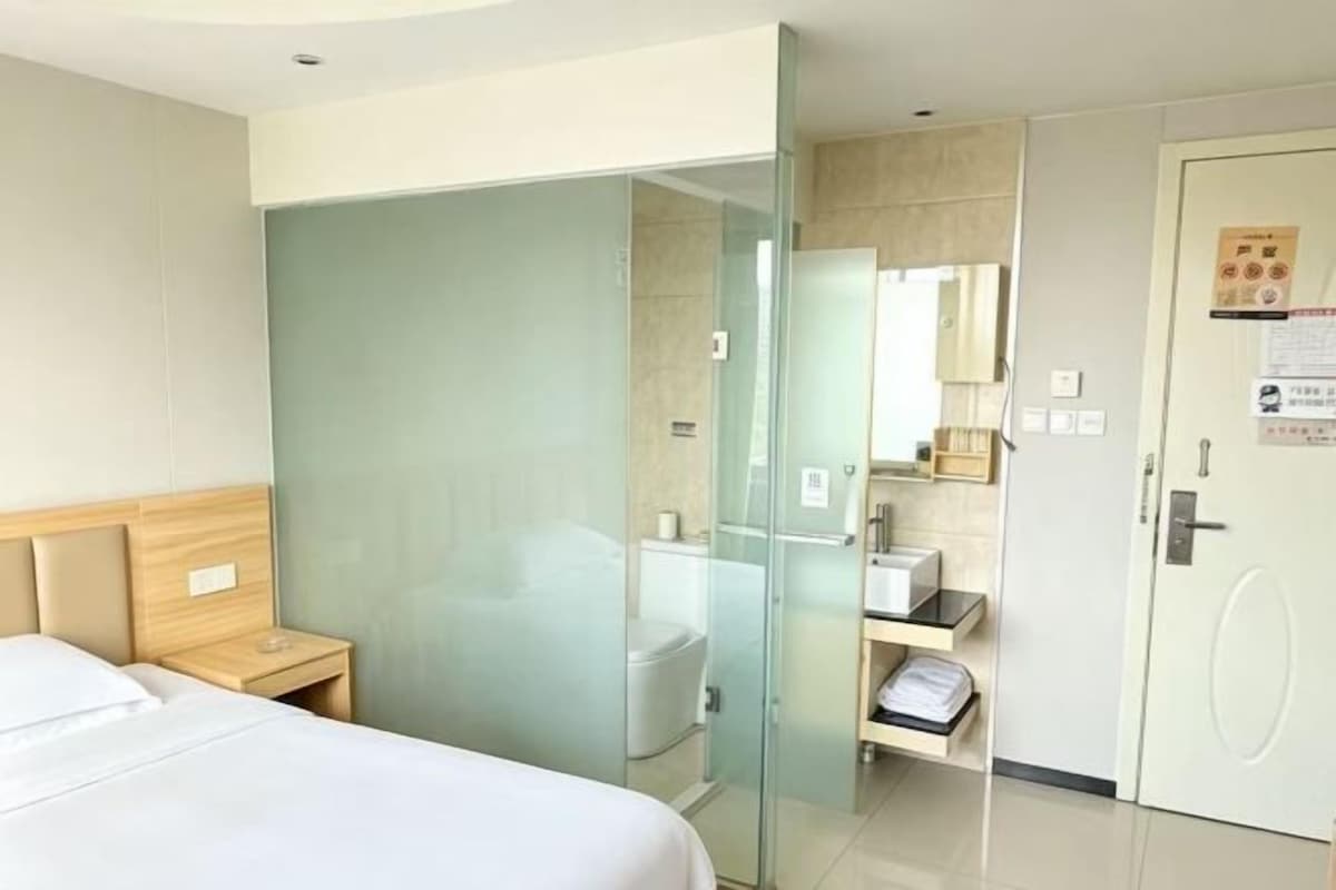 Une chambre d’hôtel comprenant un lit, une douche en cabine de verre, des toilettes et une armoire.