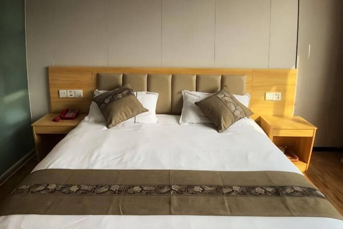 A neatly made bed with a headboard, two bedside tables, and a bedside lamp.