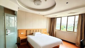 A hotel room with a bed, a wardrobe, a nightstand, and a window with a view. - 0576 Business Hotel (Taizhou)