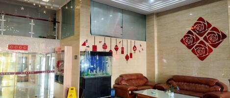 Eine Hotelhalle mit einer Sitzecke, einem Aquarium und einer Wand mit geometrischem Muster.