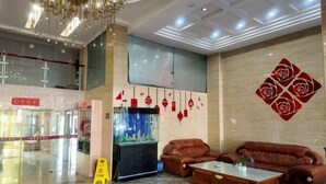 A lobby with a chandelier, a fish tank, leather sofas, and a decorative wall. - 0576 Business Hotel (Taizhou)
