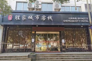 A hotel entrance with a large glass facade, a visible staircase leading up to the entrance, and a clear view of the surrounding area. - 0576 Business Hotel (Taizhou)
