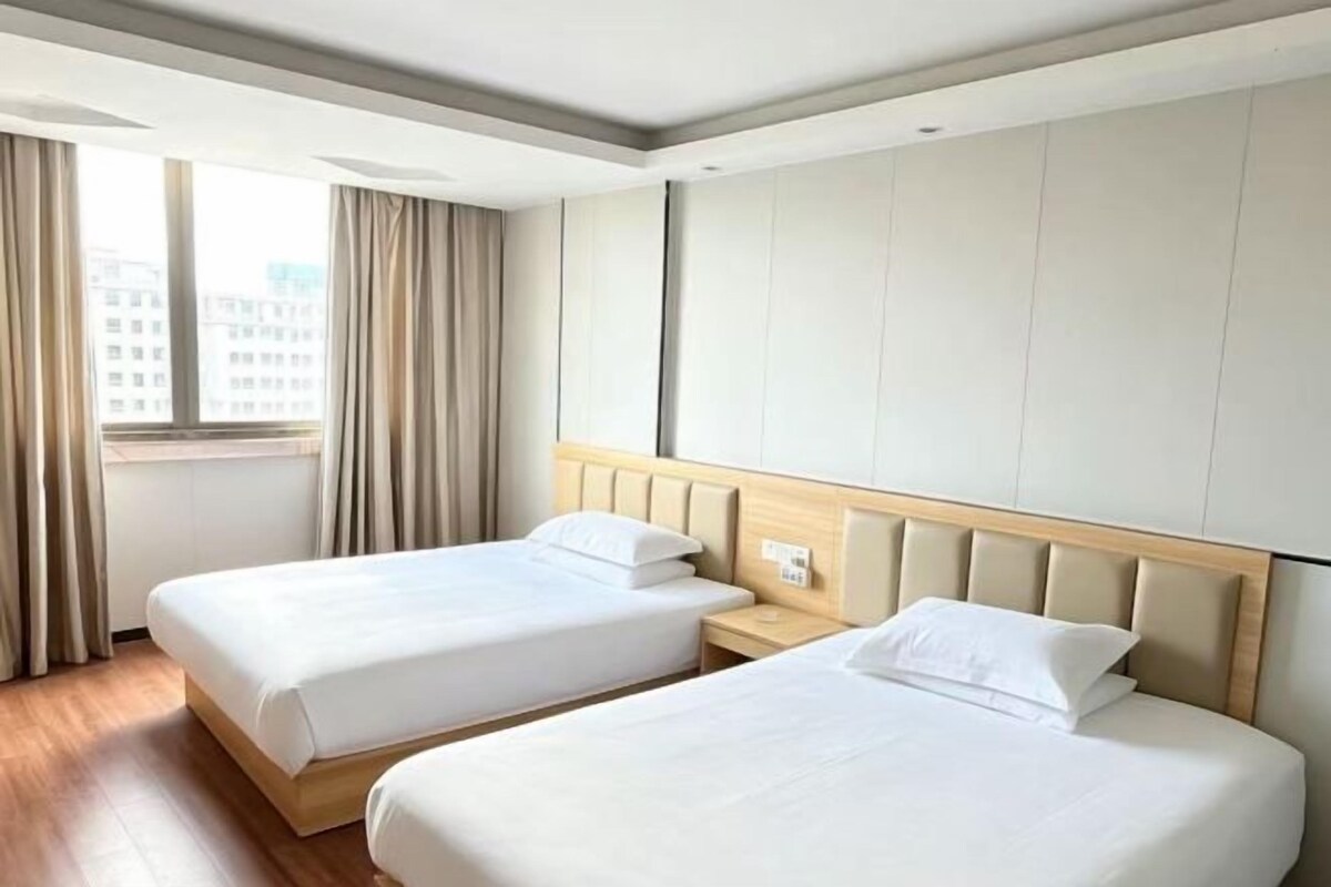 Une chambre d’hôtel avec deux lits, une fenêtre avec des rideaux et une vue sur la ville.