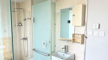 Un baño moderno con cabina de ducha de vidrio, lavamanos y espejo.