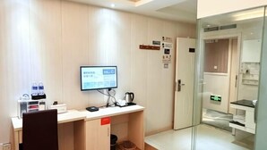 A hotel room with a desk, a television, a bed, a glass partition, and a bathroom. - 0576 Business Hotel (Taizhou)