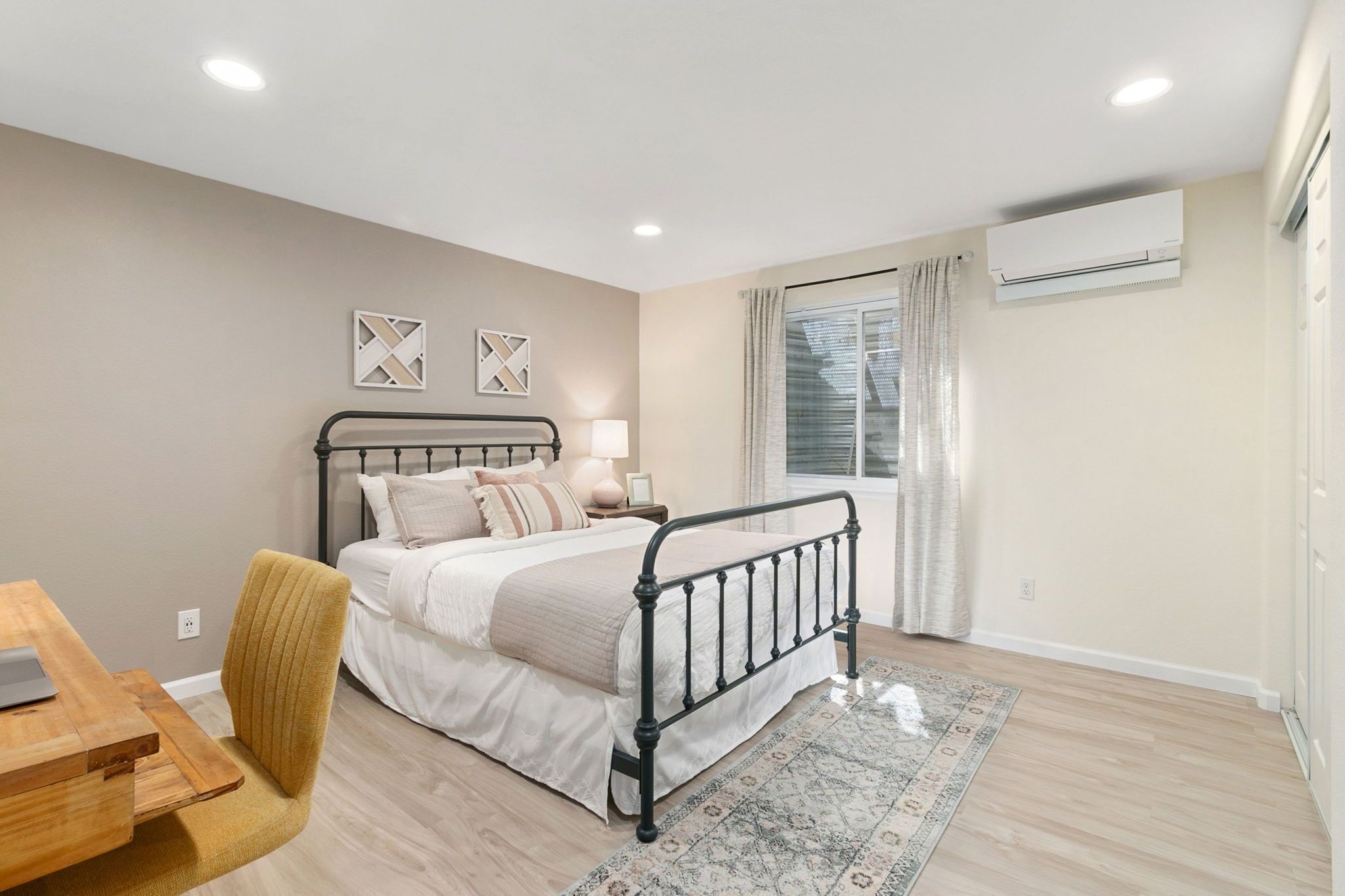 Un dormitorio con cama, mesita de noche, lámpara y ventana con cortinas.