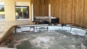 A hot tub in a wooden cabin with a view of the outside. - Le Repaire de Maltus "gîte & Spa (Lussac)