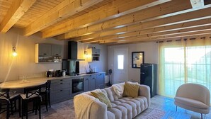 A spacious living area with a wooden ceiling, a sofa, a coffee table, and a dining table with chairs. - Le Repaire de Maltus "gîte & Spa (Lussac)