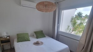 Makuuhuoneessa on suuri sänky, yöpöytä, roikkuva punottu valaisin ja ikkuna, josta avautuu näkymä vehreään maisemaan.
