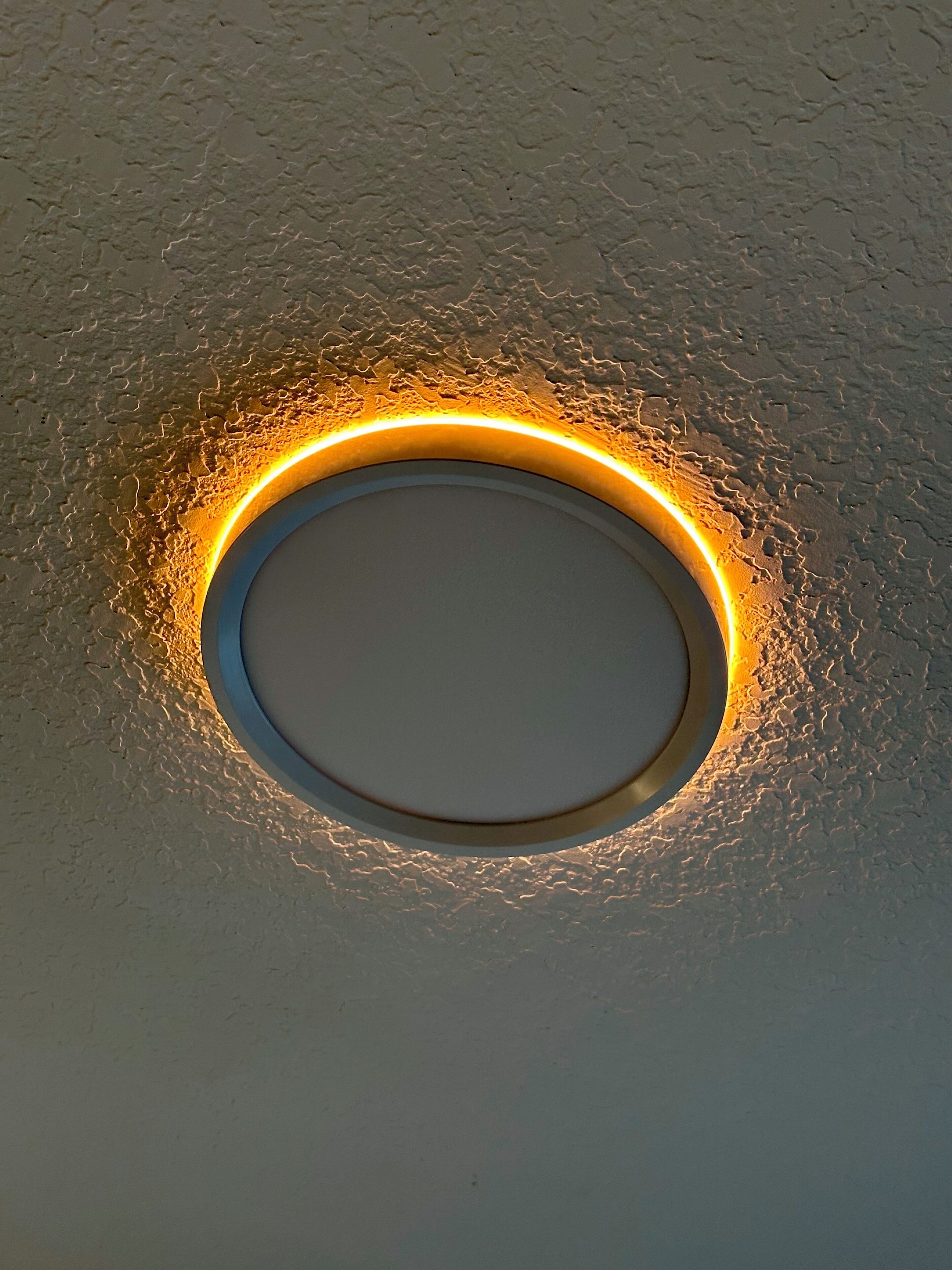 A circular recessed ceiling with a glowing light fixture.
