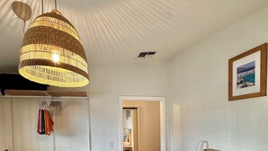 A bedroom with a bed, bedside table, hanging clothes rack, and a large woven light fixture. - Santorini Cabana in Zephyrhills (Zephyrhills)