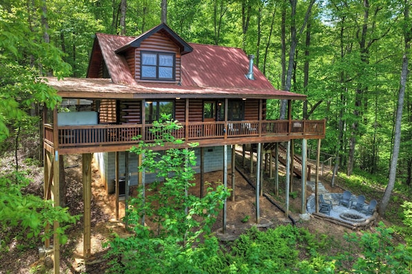 A cabin with a balcony, a chimney, and a fire pit.
