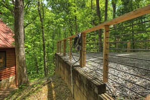 A wooden deck with metal railings, surrounded by dense green trees.