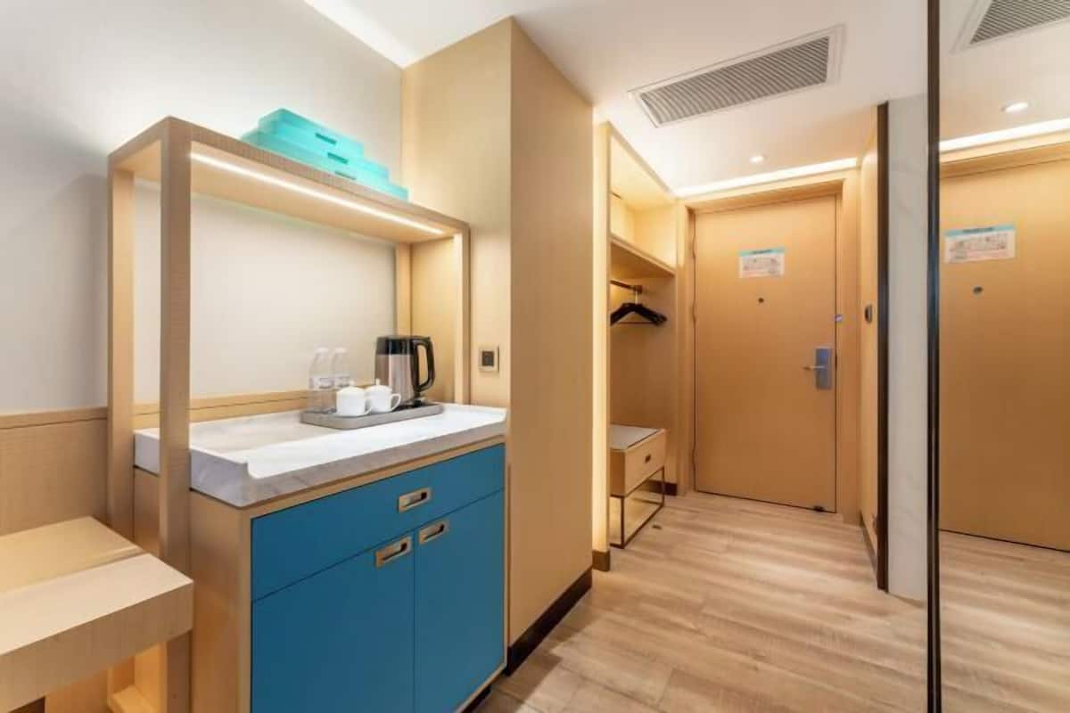 A hotel room with a kitchenette, a small table, a blue cabinet, and a wooden floor.