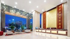 A modern hotel lobby with a reception desk, seating area, and large windows overlooking the city. - Mei Li Hua Hotel (Dezhou)