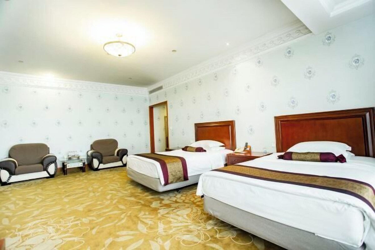 A hotel room with two beds, a sofa, a small table, and a carpeted floor.