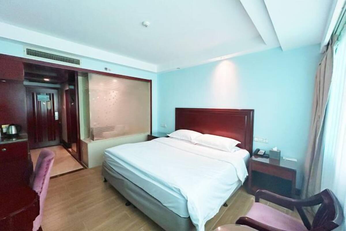 A hotel room with a bed, a desk, a chair, and a nightstand.
