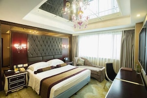 A modern hotel room with a large bed, a sofa, a desk, and a TV.