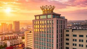A high-rise building with a distinctive crown-like structure on top, surrounded by other buildings and a sunset sky. - Mei Li Hua Hotel (Dezhou)