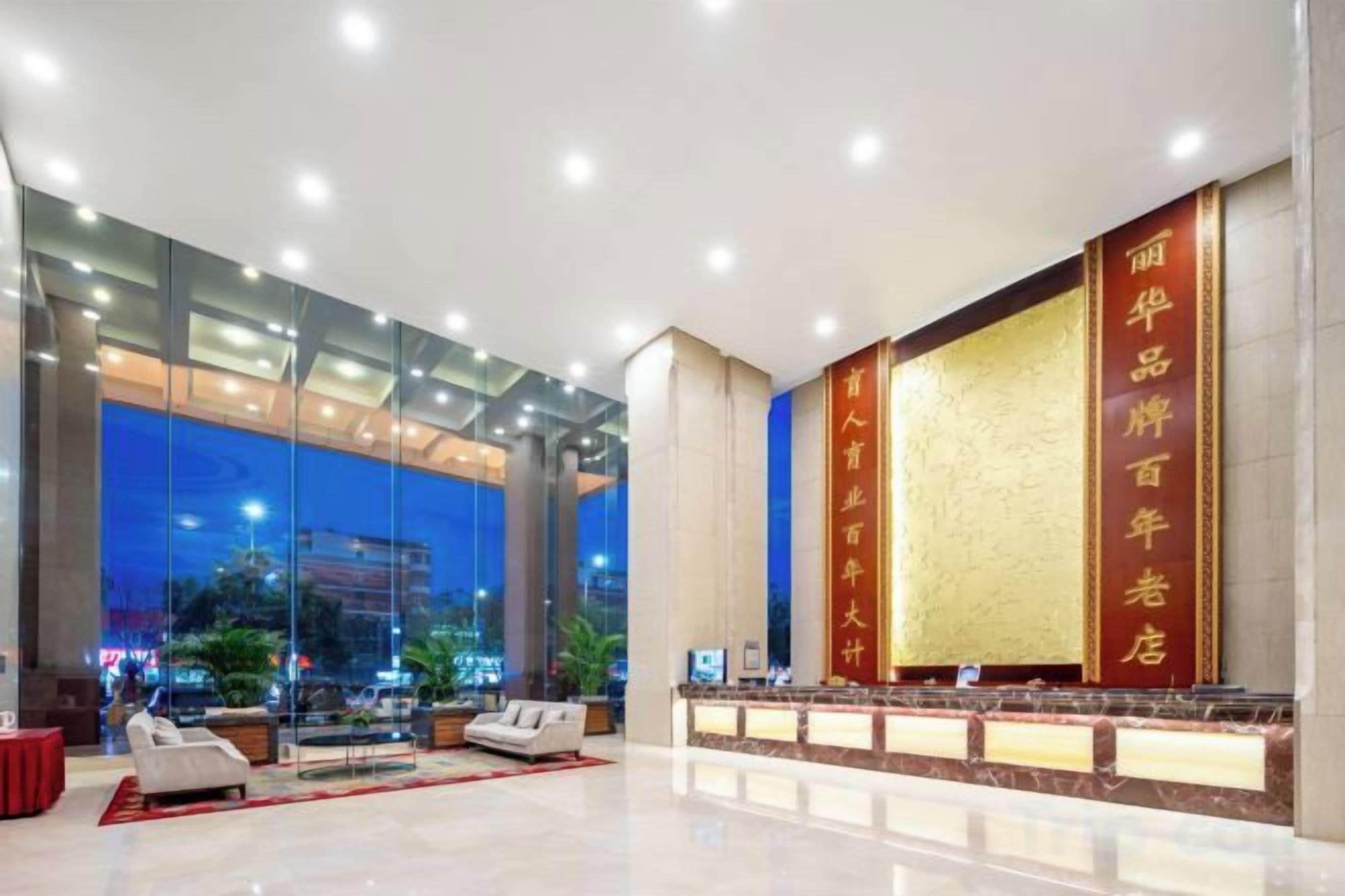A hotel lobby with a reception desk, seating area, and large windows offering a view of the cityscape.