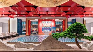 A hotel lobby with a red and blue checkered floor, a central seating area with chairs, and a decorative tree. - Mei Li Hua Hotel (Dezhou)