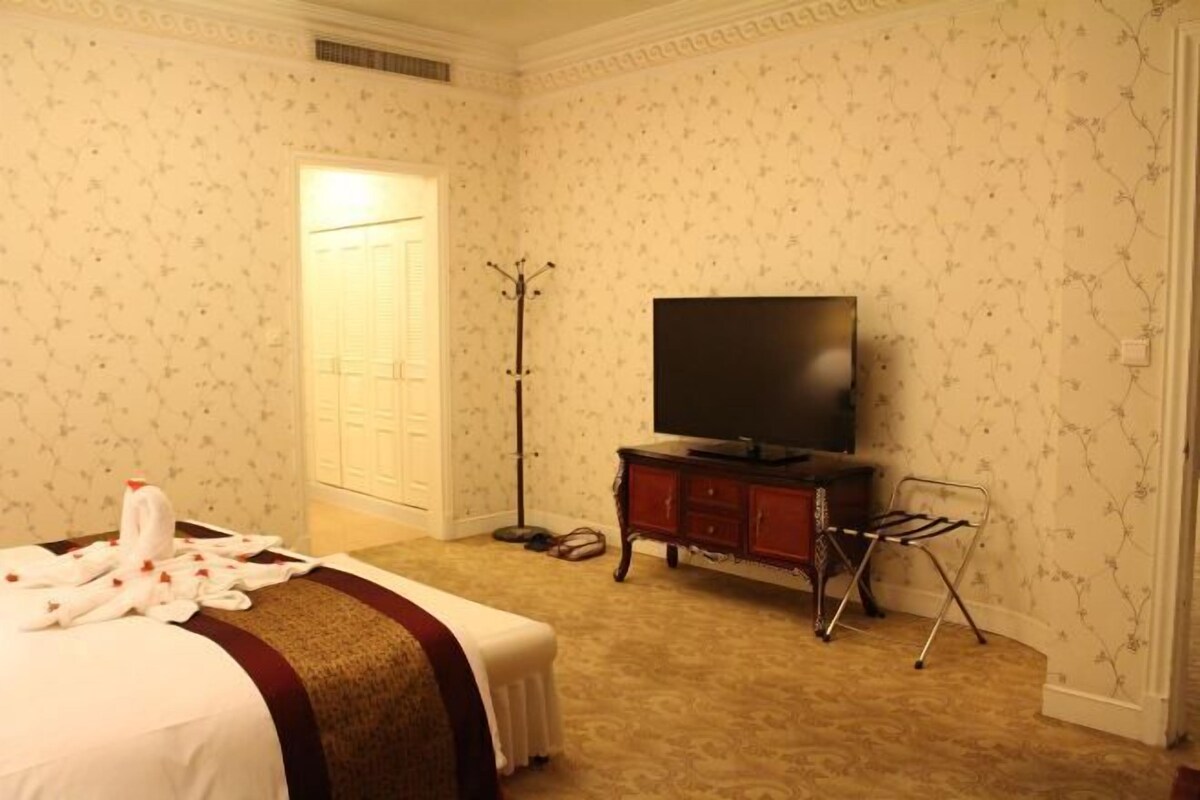 A hotel room with a bed, a television, a wardrobe, and a coat rack.