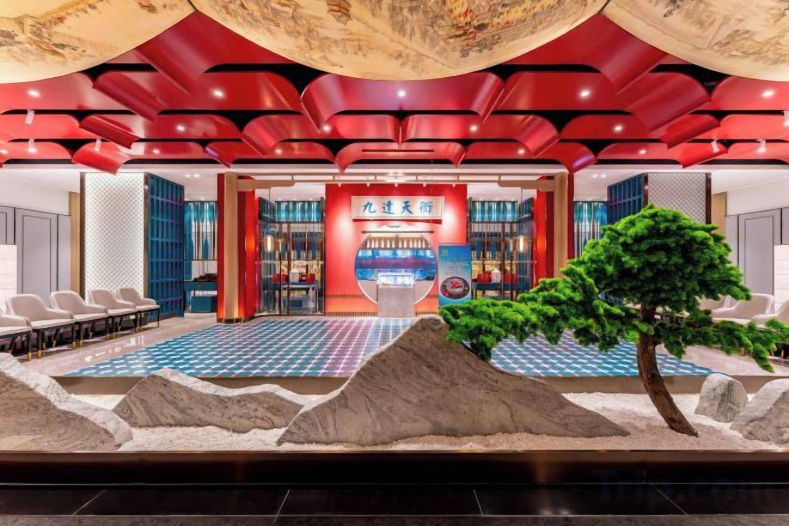 A hotel lobby with a reception desk, seating area, and a decorative indoor garden.