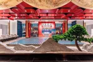 Un hall d’hôtel comprenant un comptoir d’accueil, un espace salon et un jardin intérieur décoratif.