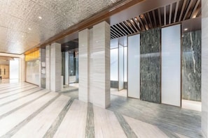A spacious lobby with marble flooring, large columns, and a modern ceiling design.