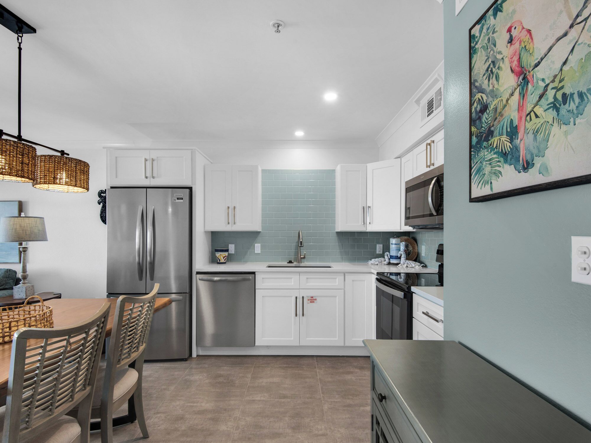 A modern kitchen with white cabinets, stainless steel appliances, and a dining area with a table and chairs.