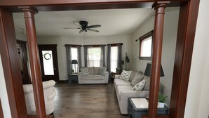 A living room with a wooden floor, a ceiling fan, and a sofa with patterned cushions. - Cozy 3 Bedroom Home (Elyria)