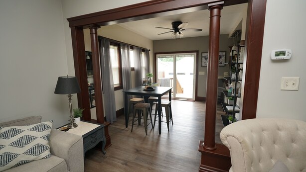 A living room with a sofa, a dining table with chairs, a lamp, and a ceiling fan. - Cozy 3 Bedroom Home (Elyria)