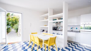 A modern kitchen with white cabinets, a dining table with yellow chairs, and a patterned floor.