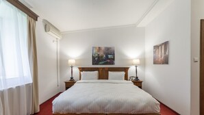 A hotel room with a large bed, two bedside tables with lamps, a painting on the wall, and a window with curtains. - Arc de Triomphe by CityBookings (Bucharest)