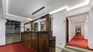 A hallway with a red carpet, wooden paneling, and a staircase. - Arc de Triomphe by CityBookings (Bucharest)