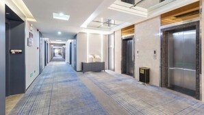 A modern hotel hallway with a long corridor, elevators, and a reception area. - GreenTree GEM International Hotel (Zaozhuang Station Municipal Government) (Zaozhuang)